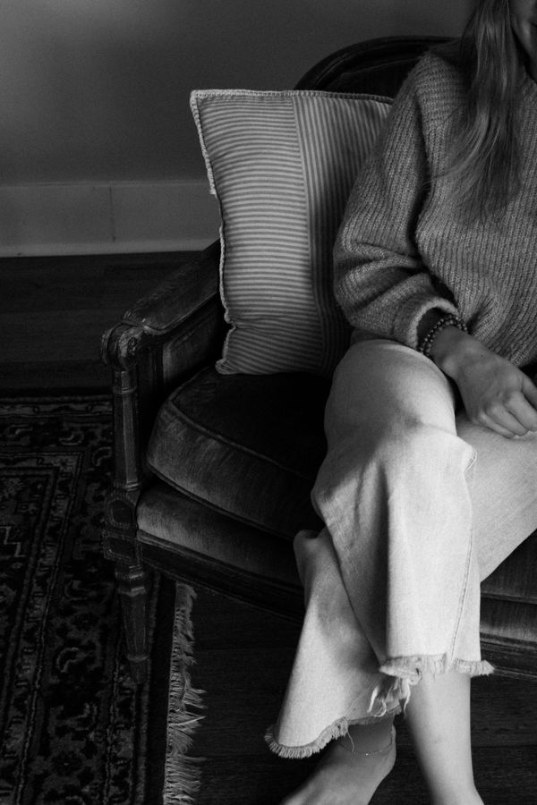Black and white photo of a person seated in a vintage armchair