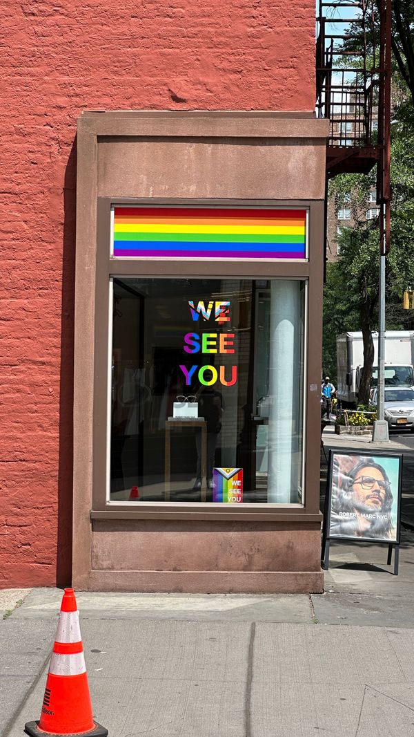Storefront window with a rainbow banner and a We See You message