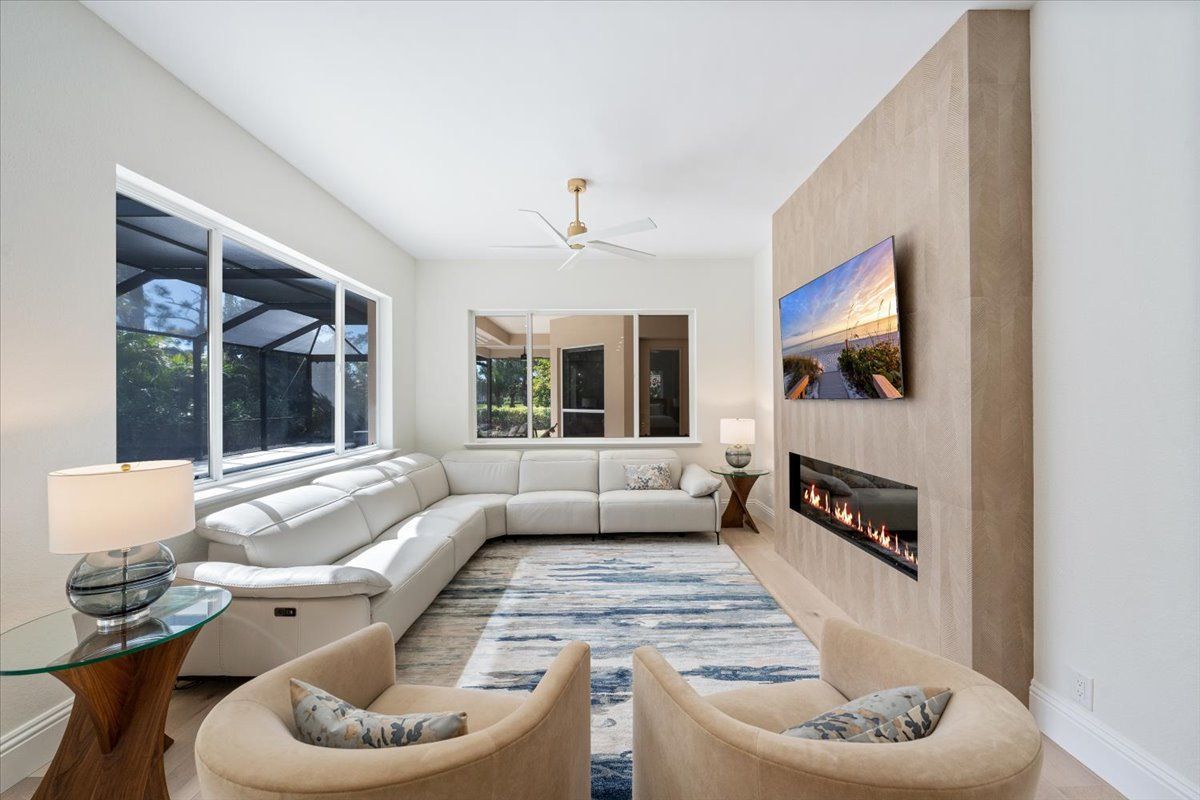 A living room with a couch, two chairs, a fireplace and a flat screen tv.