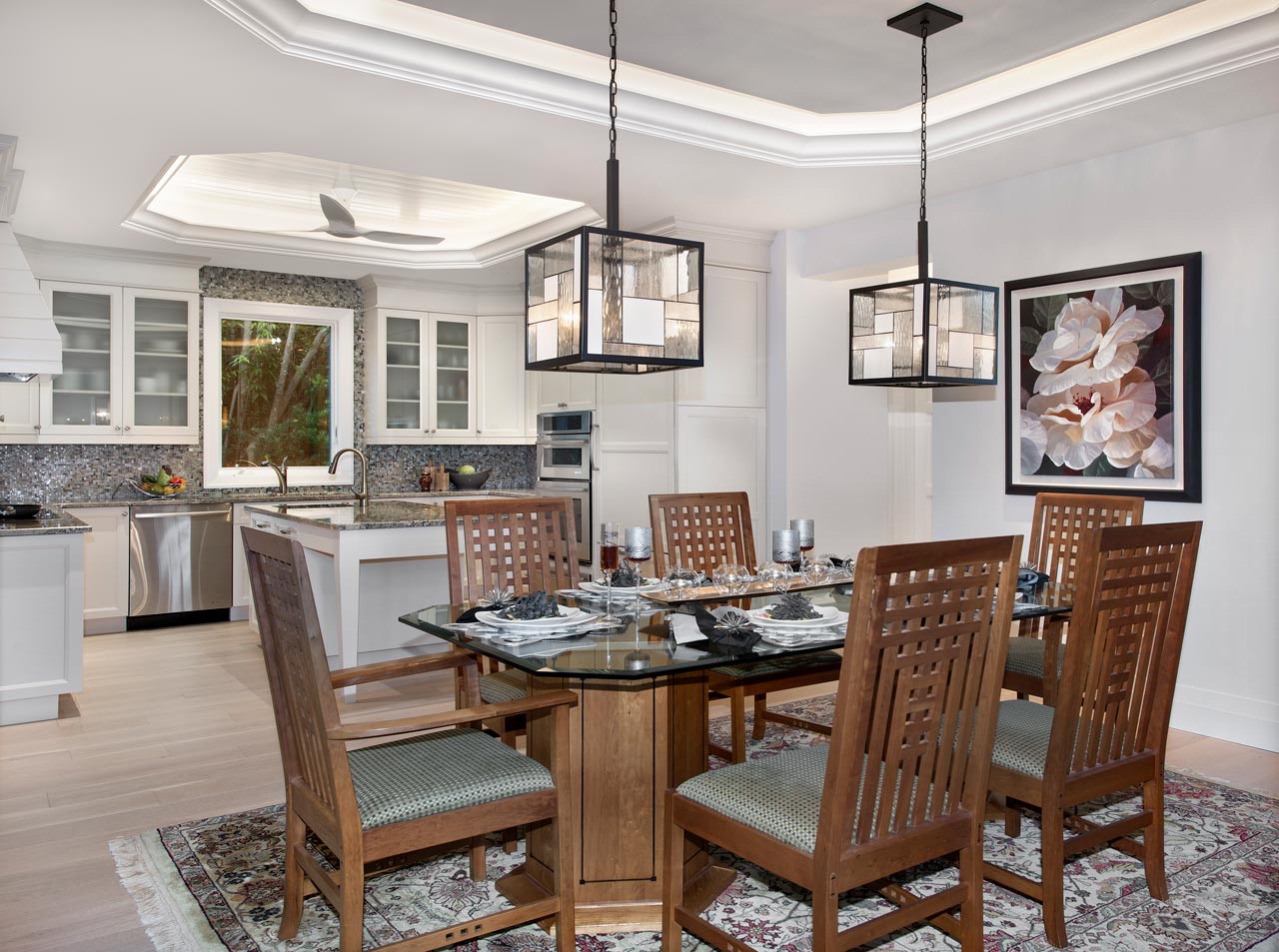 A dining room with a table and chairs and a kitchen in the background.
