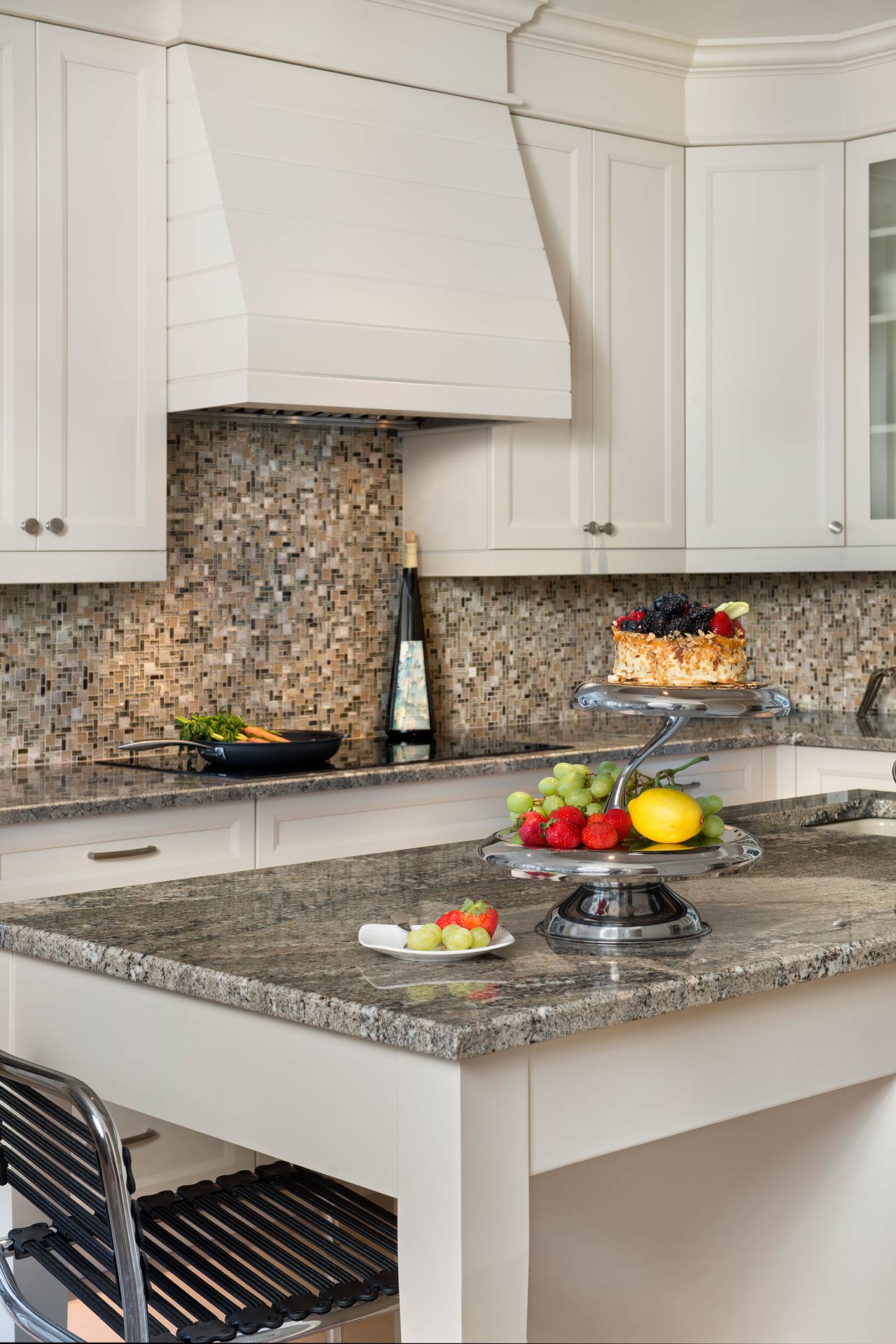 A kitchen with a granite counter top and white cabinets.