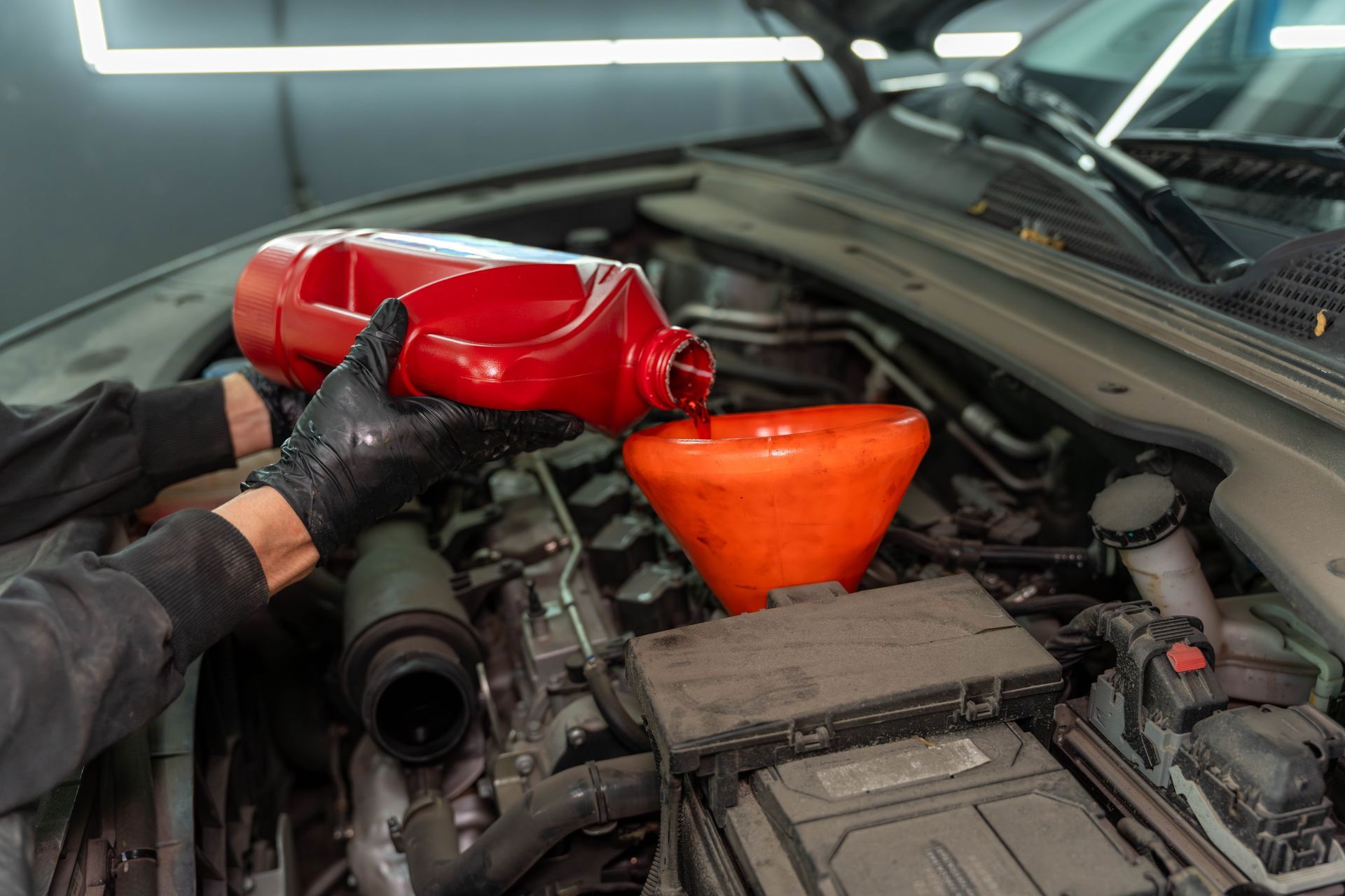 Mechanic pours red fluid in a transmission fluid exchange