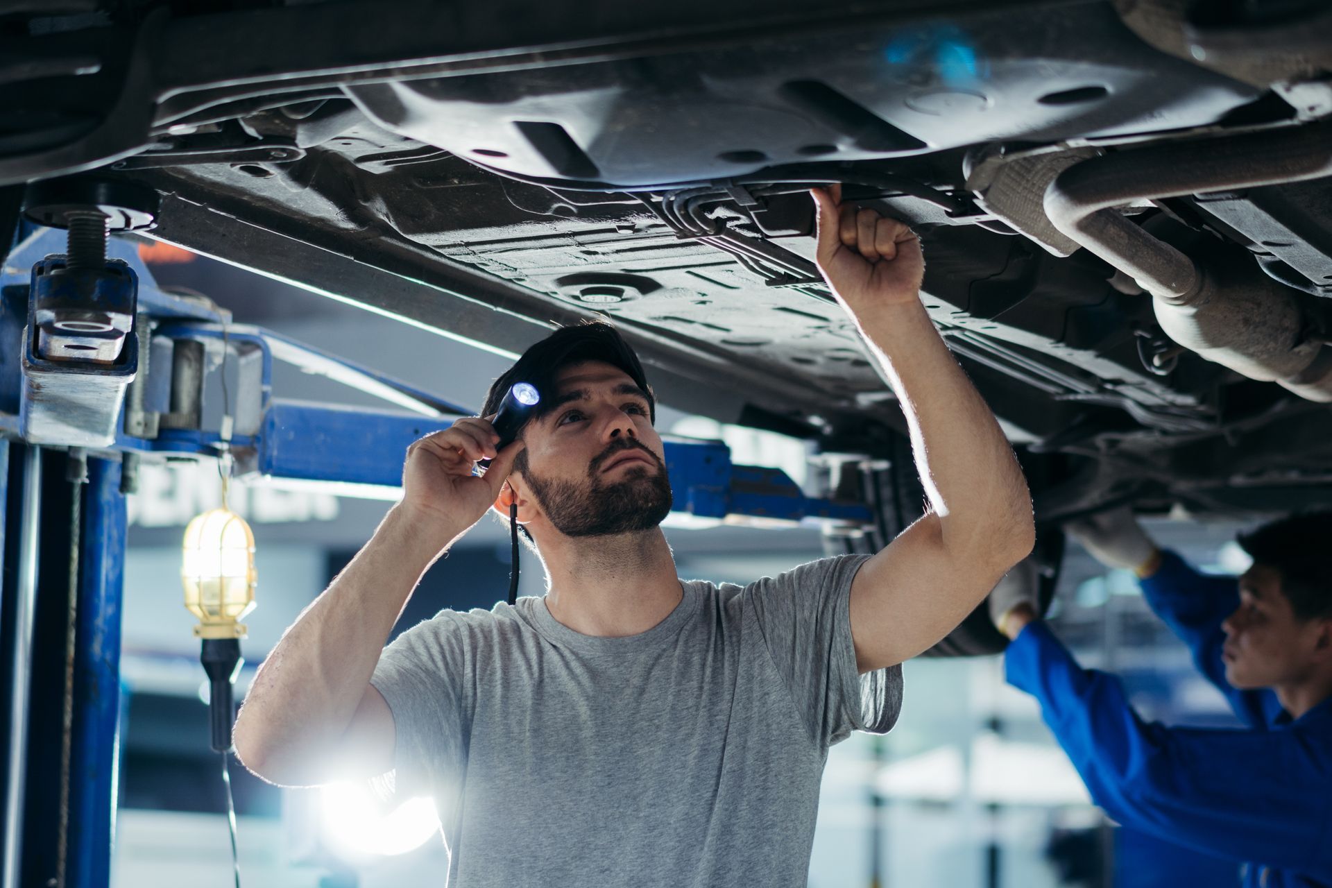 Technician inspecting a vehicle underbody during auto transmission repair