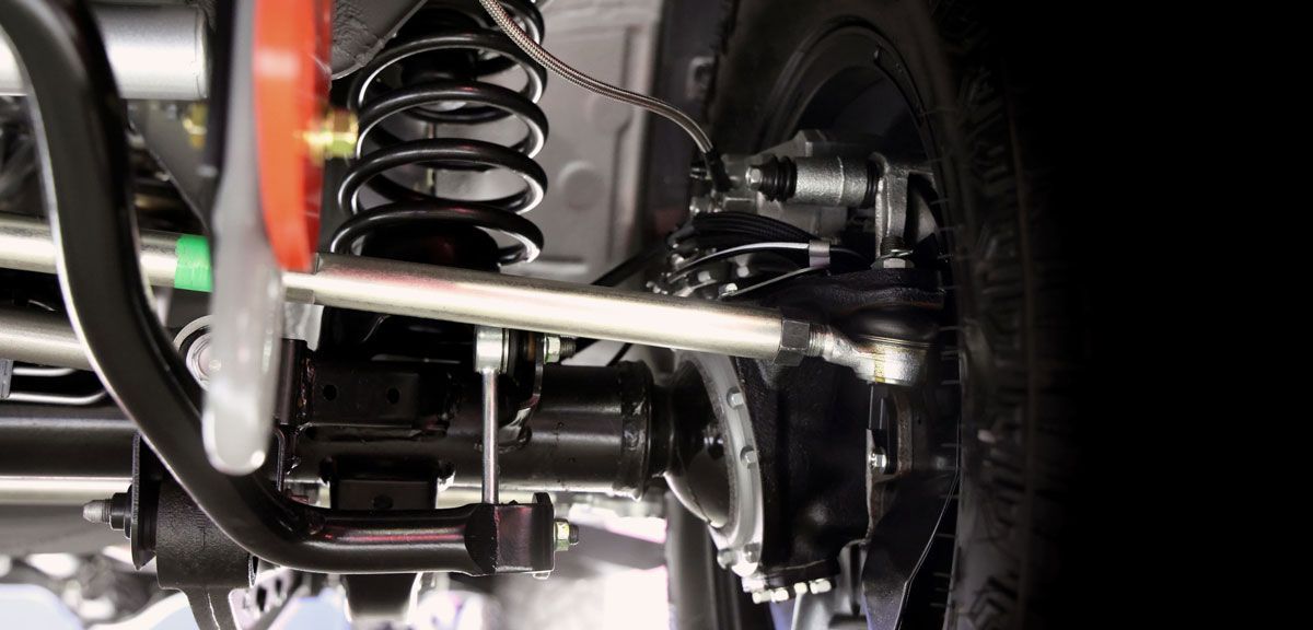 Undercarriage of a vehicle with suspension components, including a coil spring and axle.