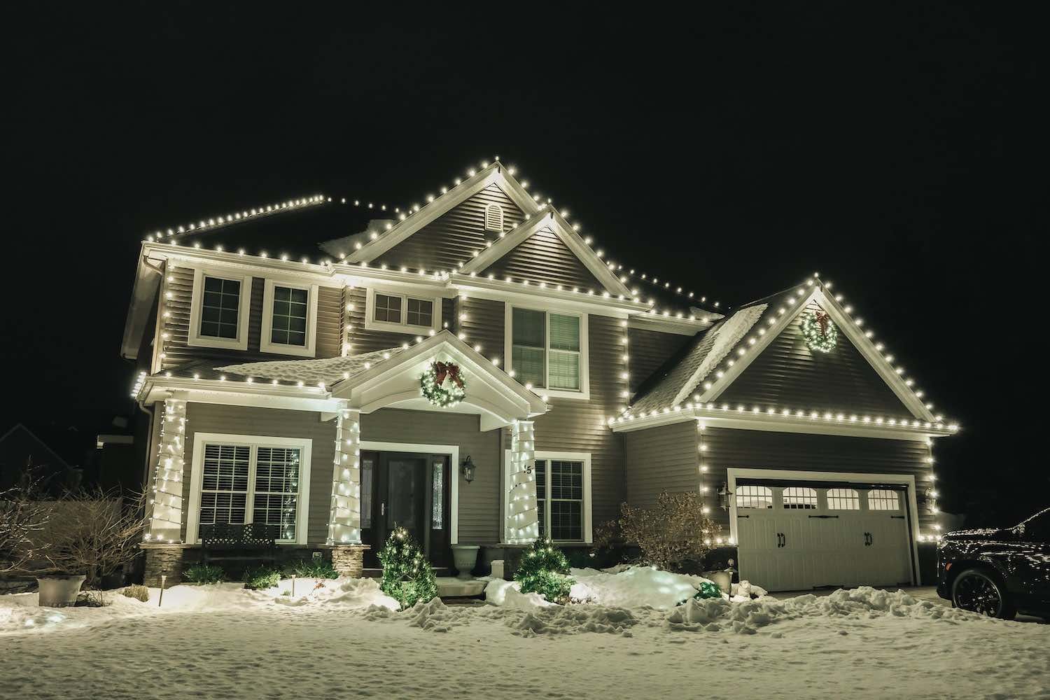 A large house is decorated with christmas lights at night.
