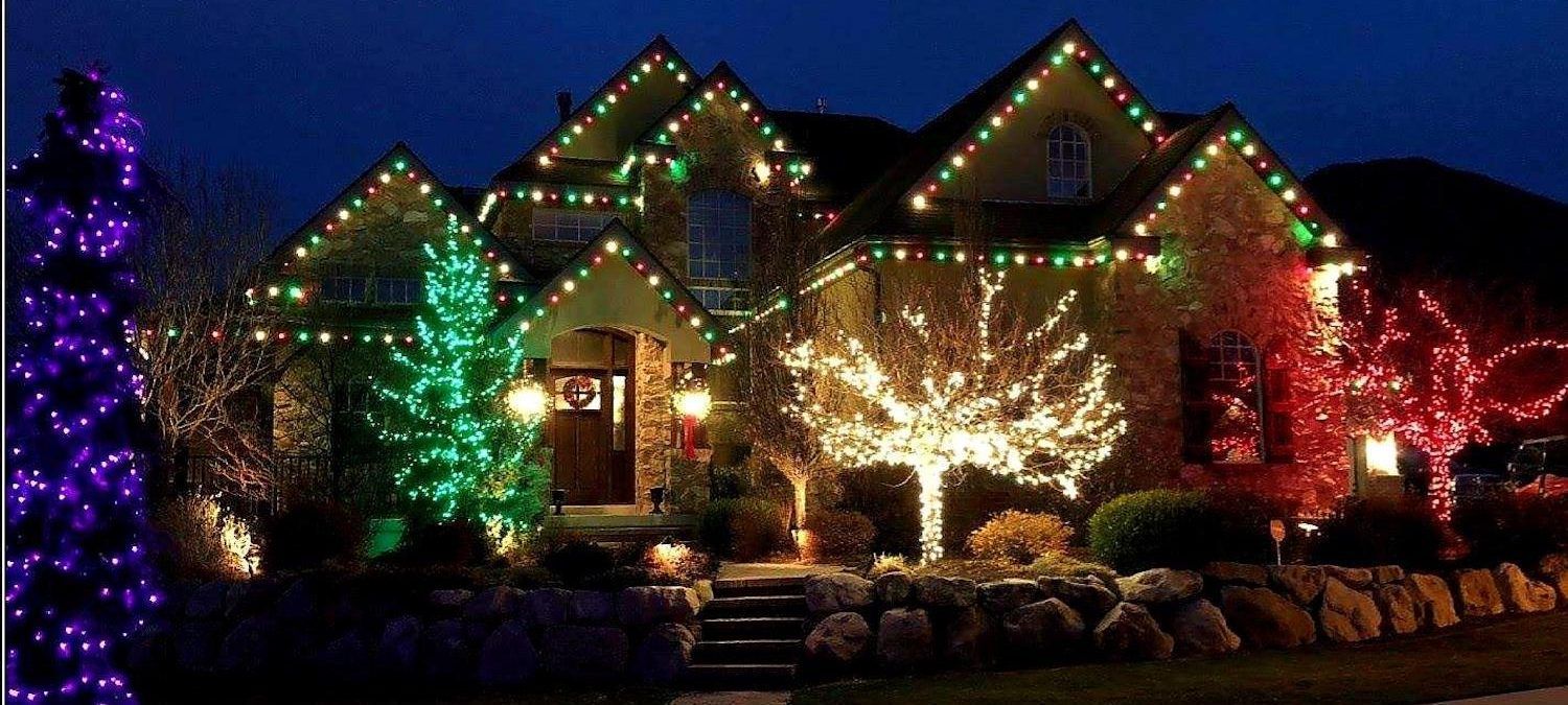 A house is decorated with christmas lights and trees