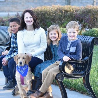 Maaggie Nurrenbern and hthree children are sitting on a park bench with a dog