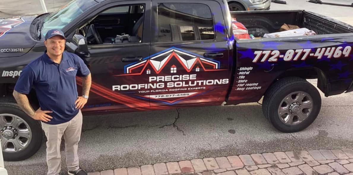 A professional in a polo shirt stands beside a dark pickup truck branded with the Precise Roofing Solutions logo.