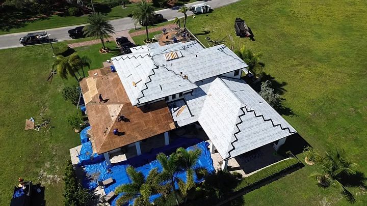 Aerial view of a house roof undergoing repair, featuring sections of brown plywood underlayment and white roofing material.