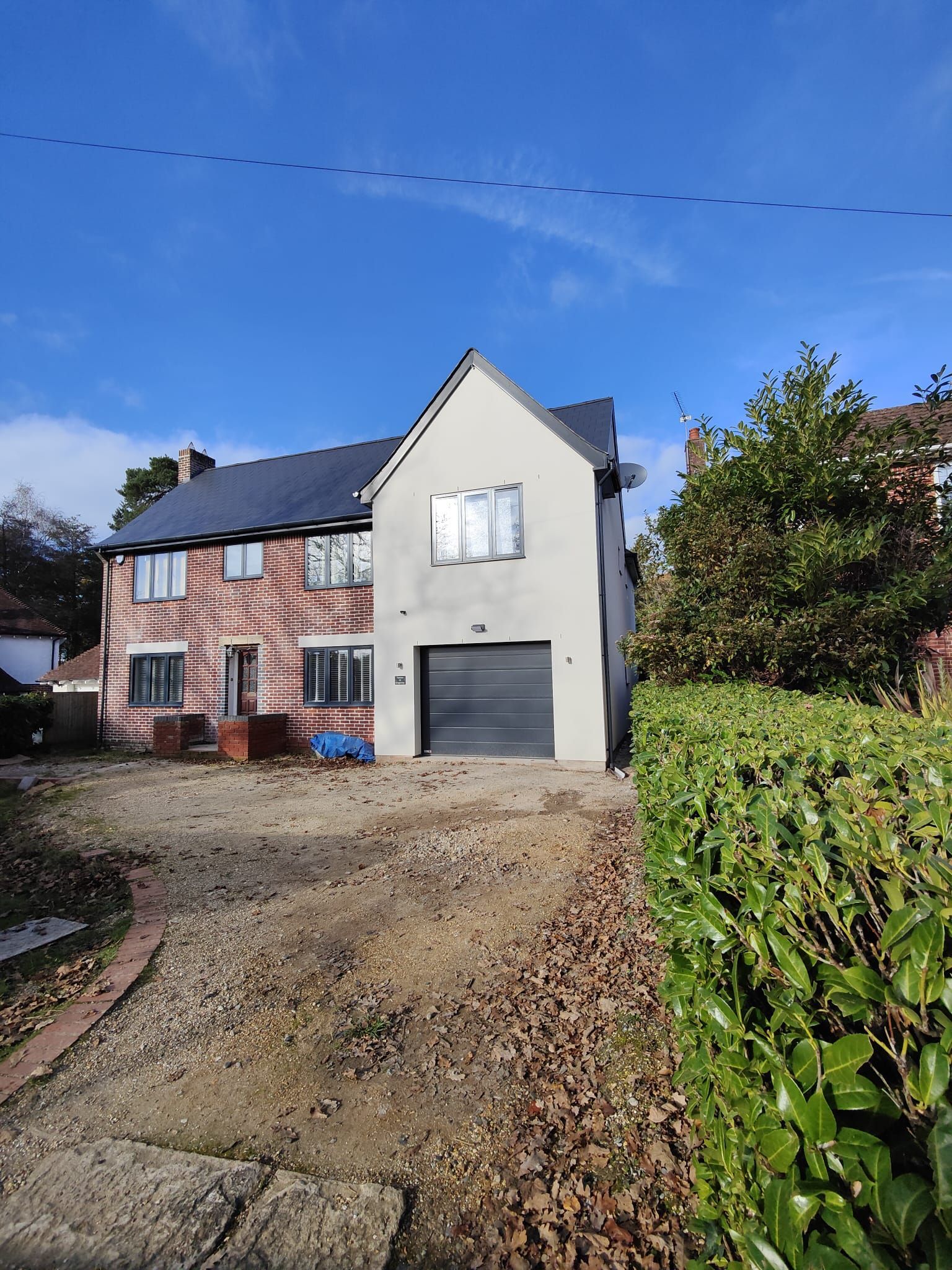 A large brick house with external render, a garage and a driveway in front of it.