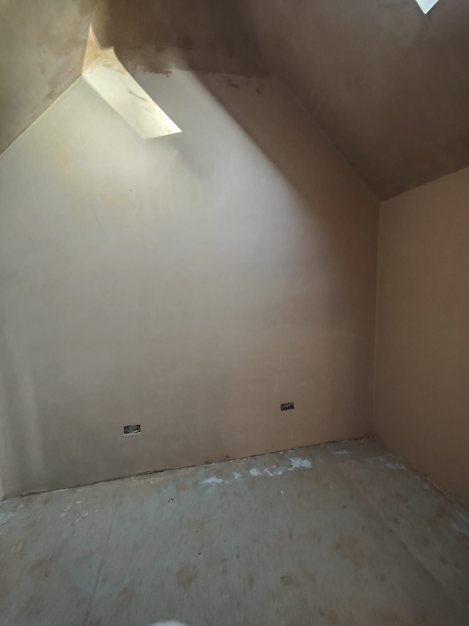 An empty room with a skylight in the ceiling.