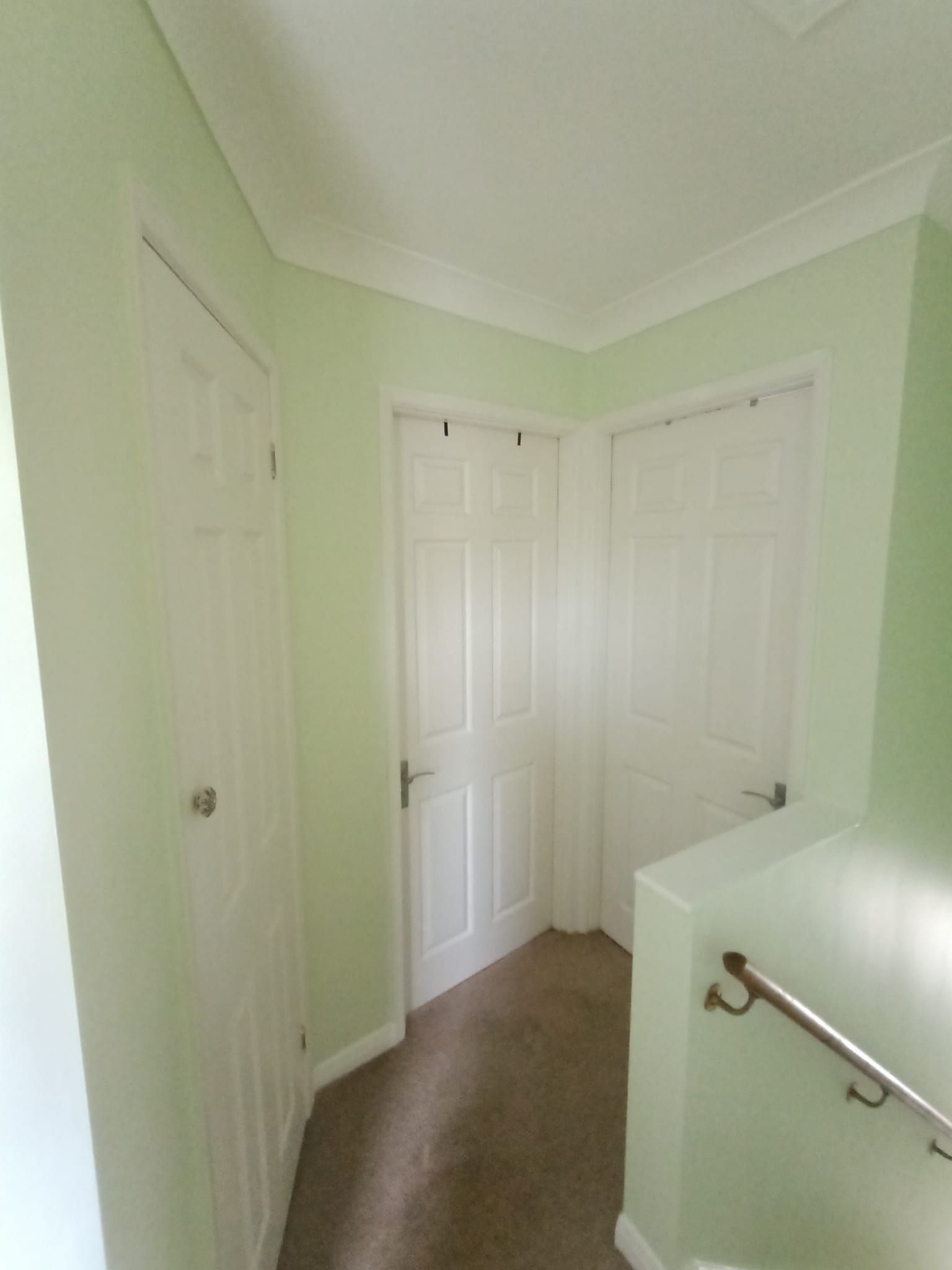 A hallway with white doors and stairs in a house.