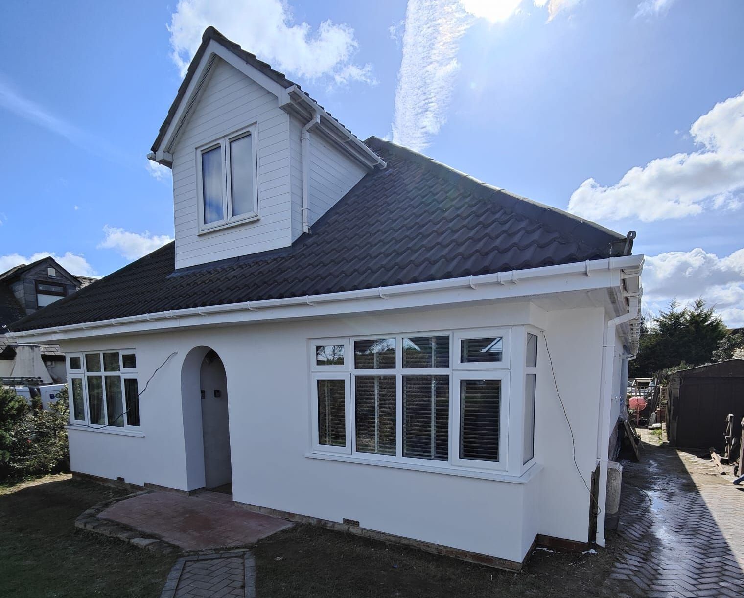A white house with a black roof and a lot of windows and external rendering and insulation