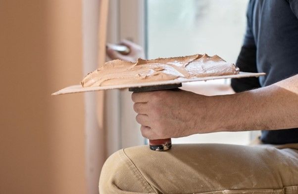 A man is plastering a wall with a trowel.