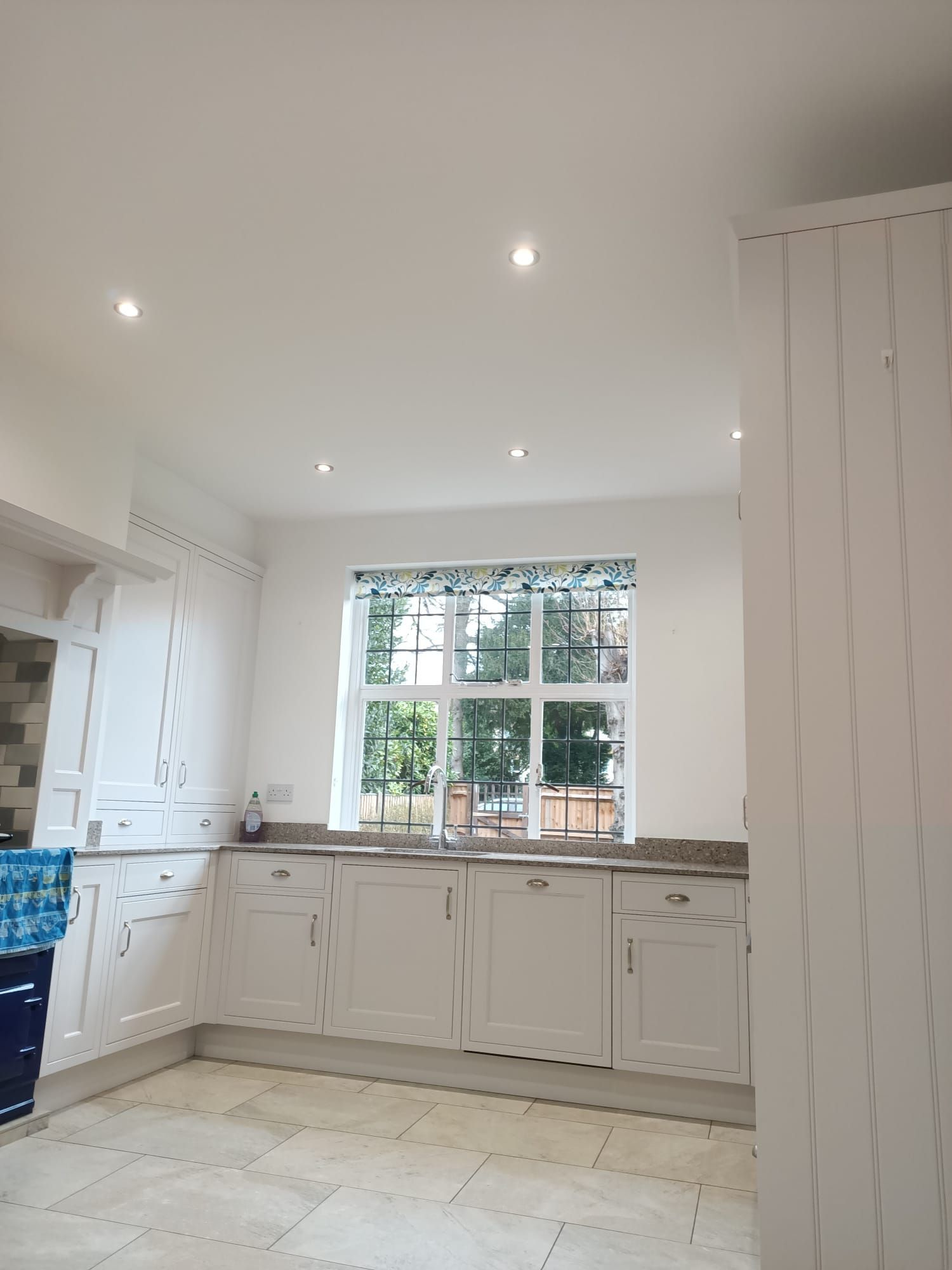 A kitchen with white cabinets and a large window.