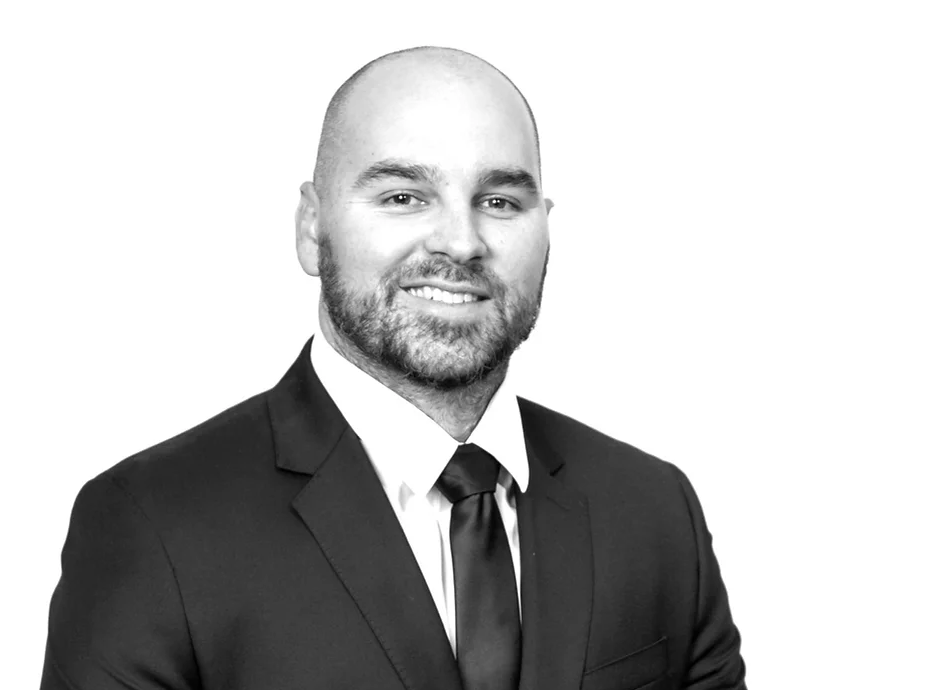 A man in a suit and tie is smiling in a black and white photo.