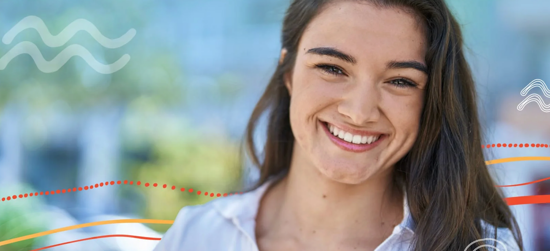 Smiling woman in a white shirt outdoors with blurred greenery in the background.