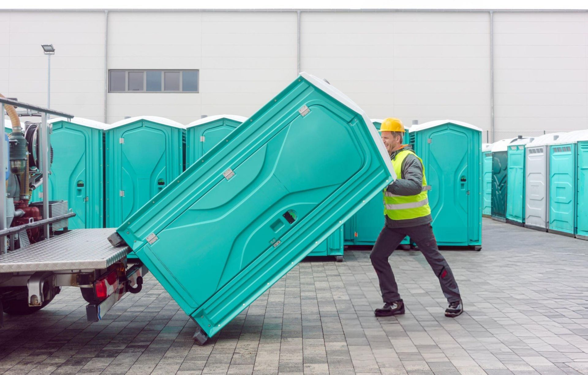 A man organizes and loads portable toilets in a warehouse for efficient portable toilet rental.
