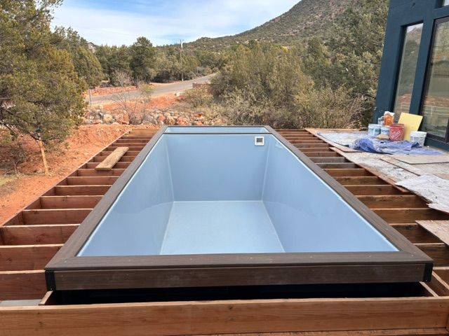 Rectangular pool in wooden frame, set against a backdrop of trees and a mountain.