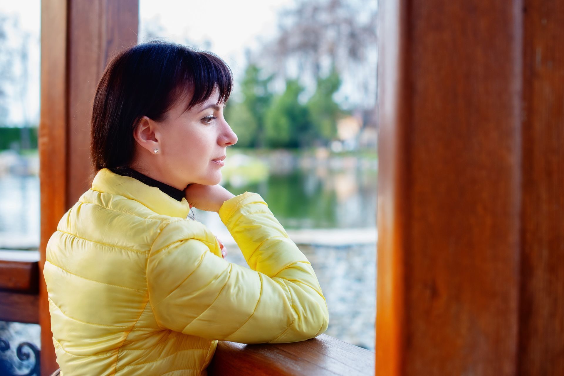 Woman sitting thoughtfully by a window, reflecting on social anxiety and whether therapy in Petaluma