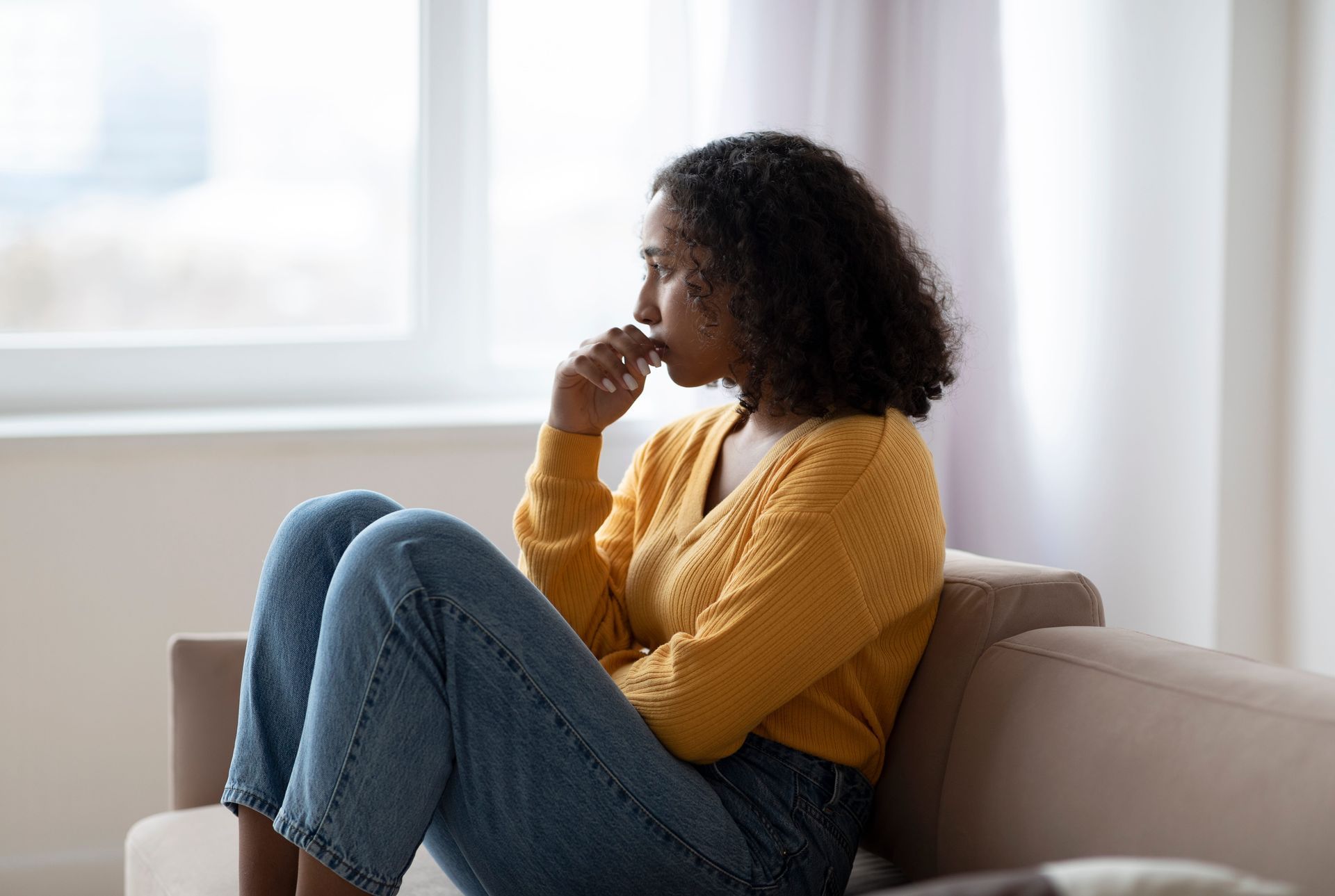 Woman sitting alone looking thoughtful, reflecting on signs of covert narcissism in her relationship