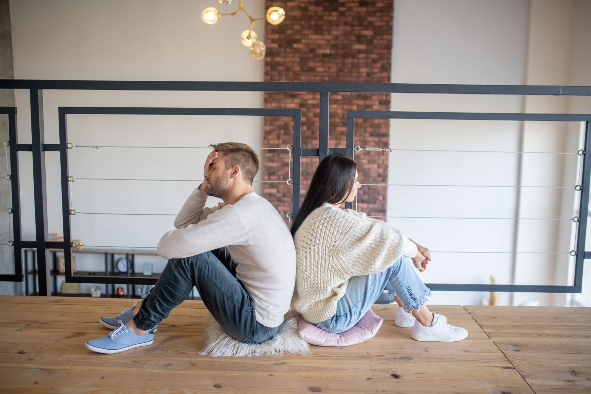 Couple sitting apart on a couch in silence, reflecting on emotional affair recovery