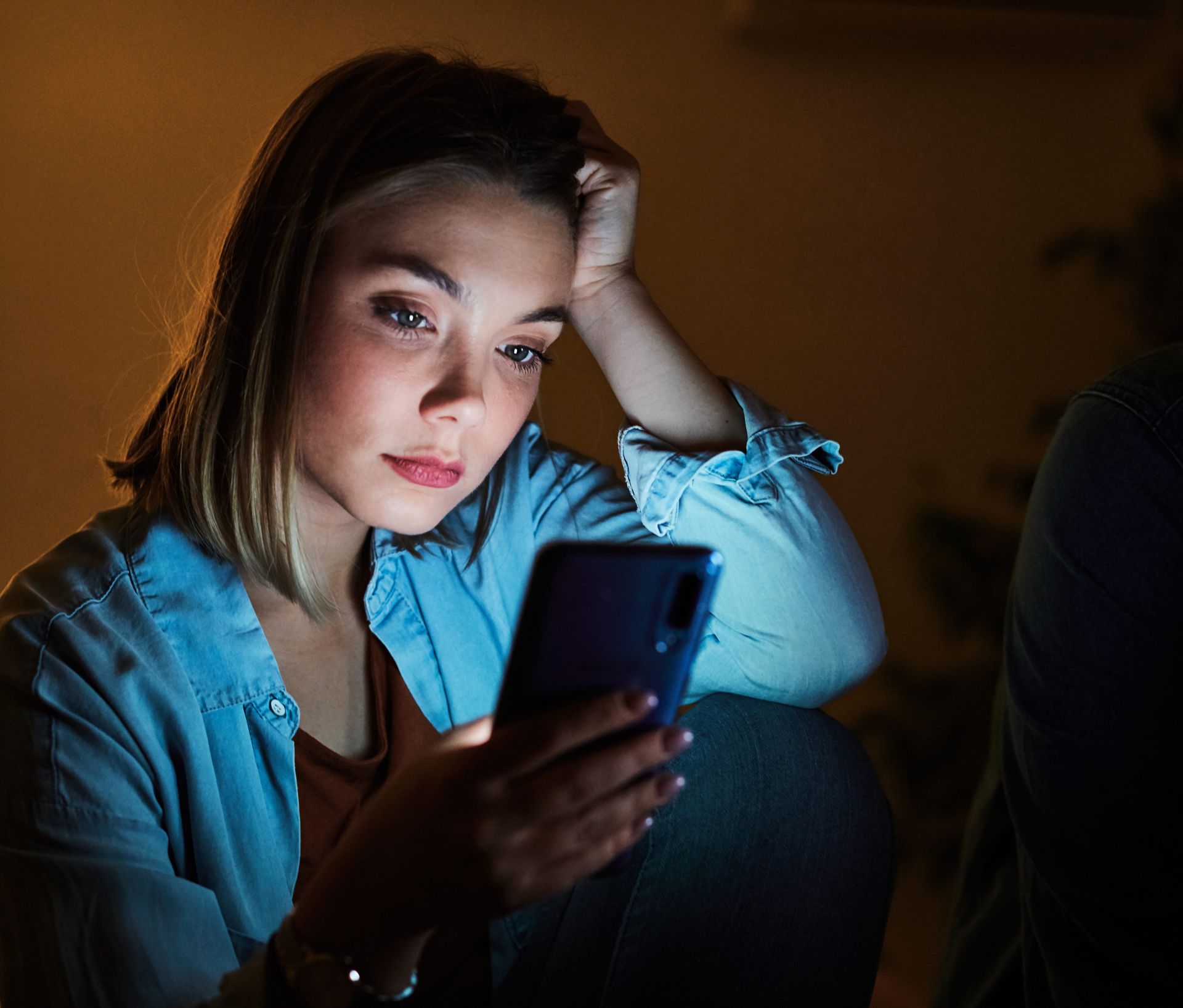Woman sitting alone looking at her phone overthinking in a relationship,