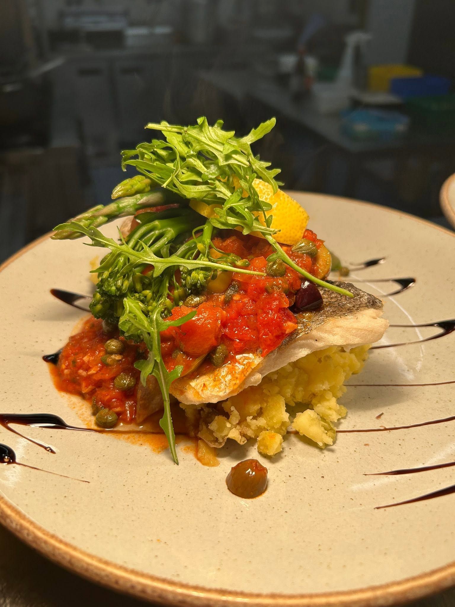 The Bush Inn, St Hilary, Cowbridge | Gourmet plated fish dish topped with greens and red sauce on a ceramic plate.