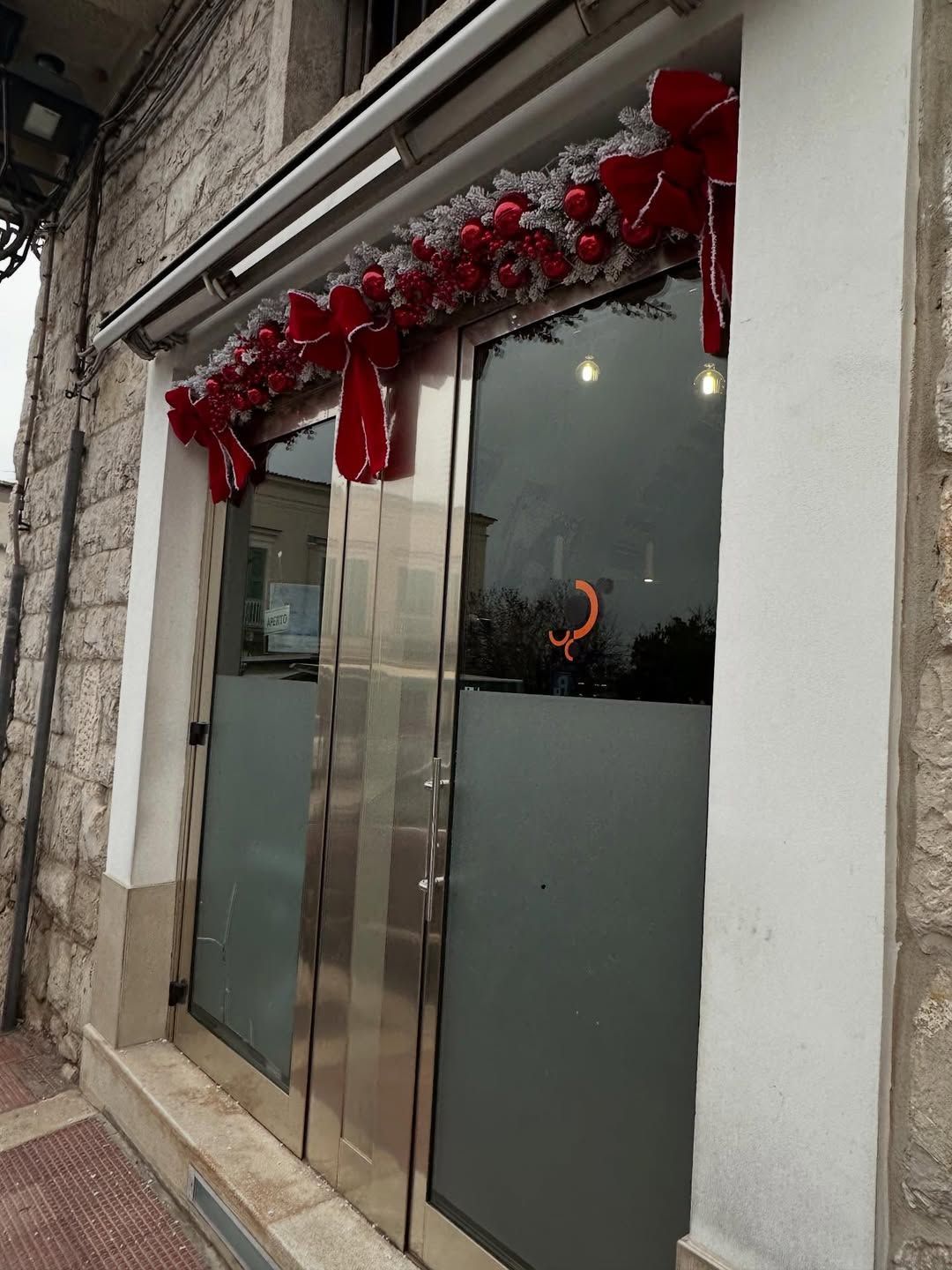 Vetrina con doppie porte a vetri decorate con ghirlande e ornamenti natalizi rossi.