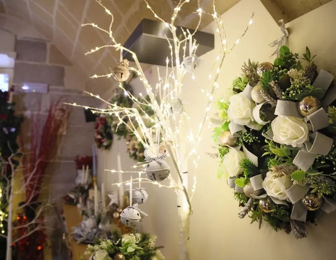 Ghirlande floreali da parete con rose bianche e luci soffuse in un corridoio illuminato da una luce tenue.