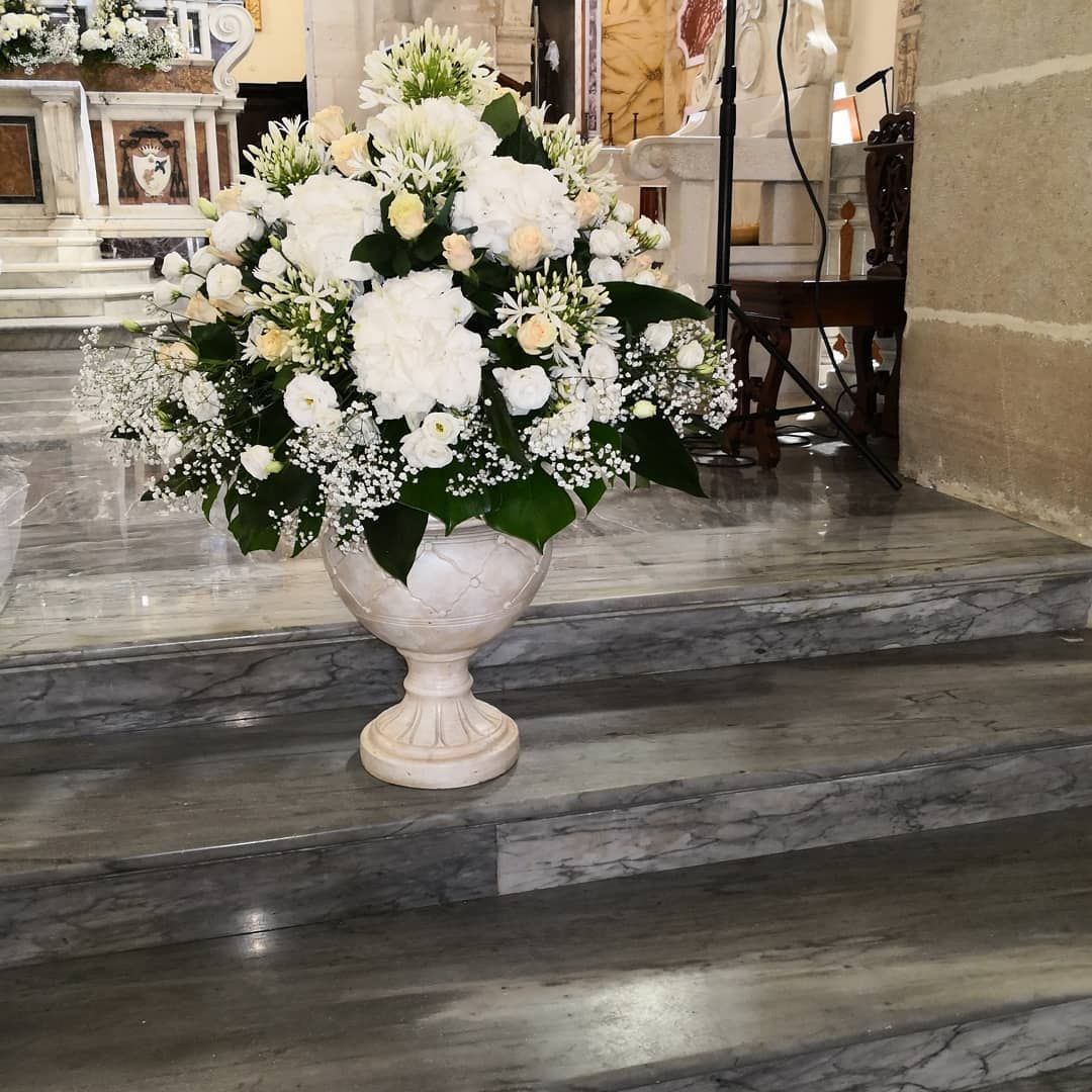 Composizione floreale bianca in un vaso decorativo sui gradini della chiesa, vicino all'altare.