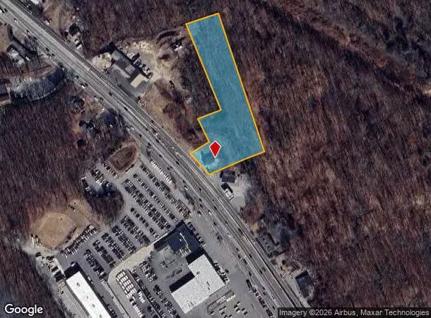 Satellite view of a blue L-shaped property outlined in yellow beside a road and parking lot