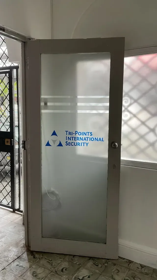 Puerta de cristal con logotipo azul en una entrada interior alicatada.