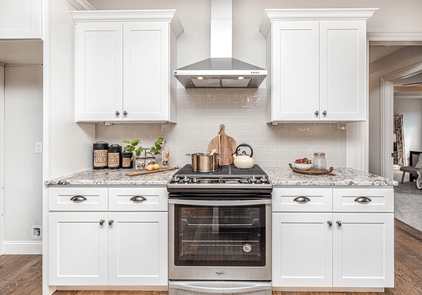Picture of kitchen with stove and cabinets. Cabinets doors and drawers were re-painted with a fresh coat of white.