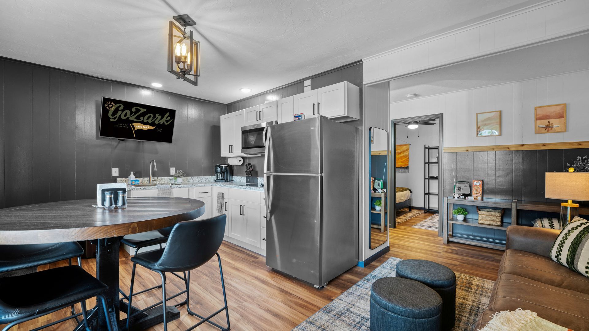 A modern kitchen with white cabinets and a stainless steel fridge next to a dining area with a dark wood table and chairs.