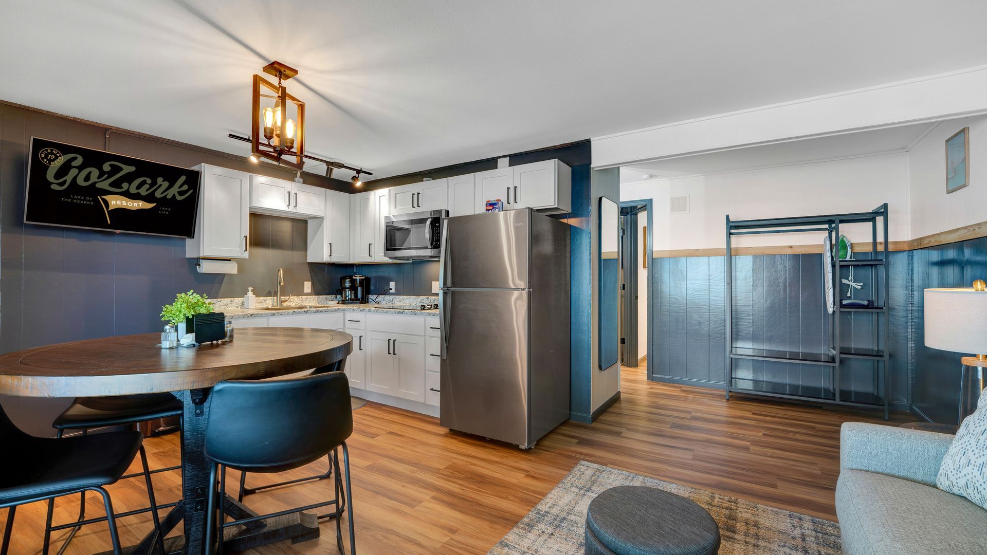 A kitchen and dining area with a wood table, black chairs, stainless steel refrigerator, and dark blue accent walls.