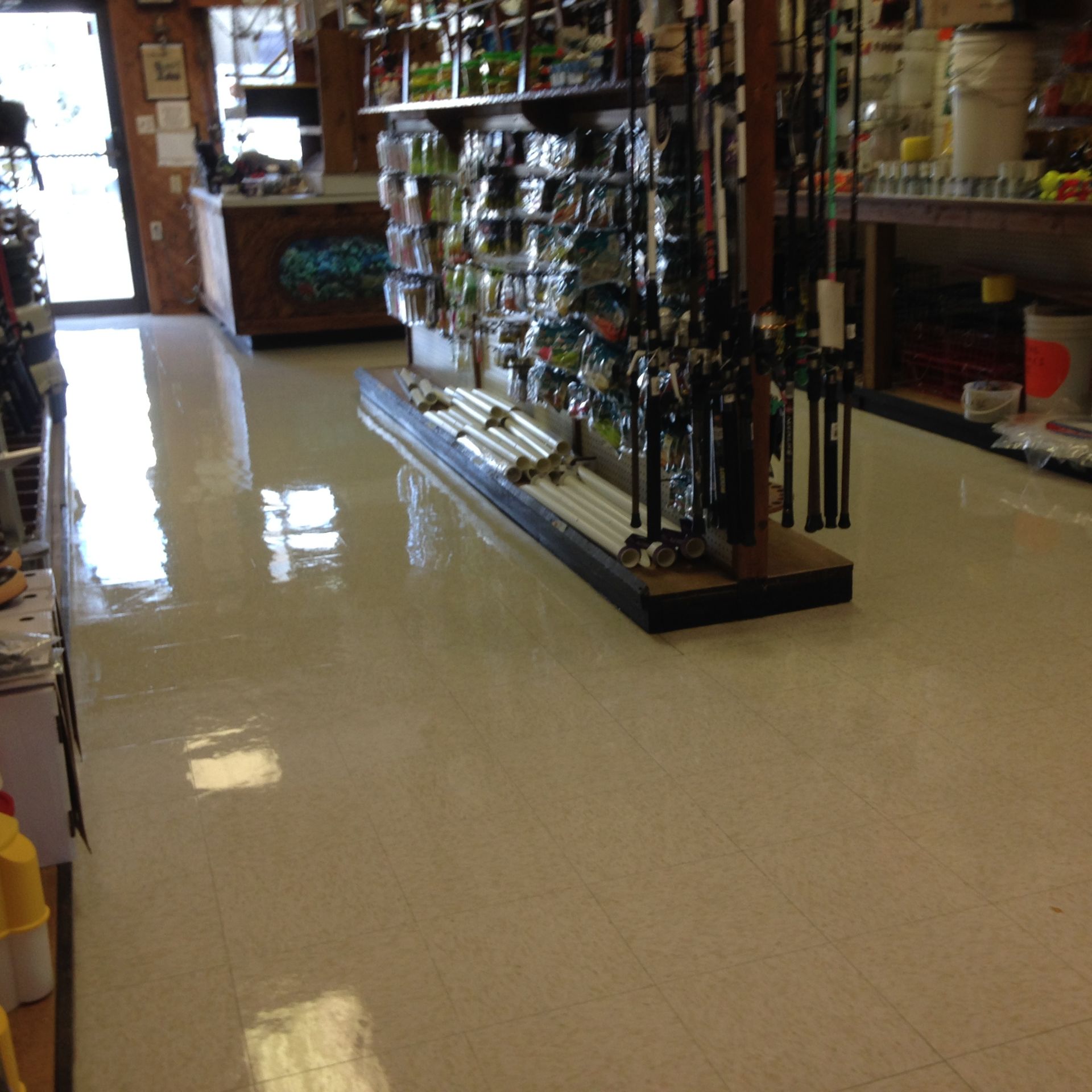Interior of a fishing supply store with shiny white floors and shelves stocked with fishing equipment.