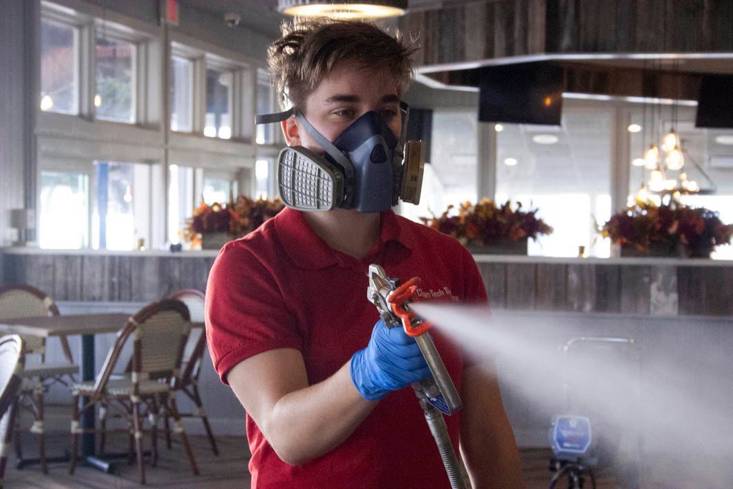 Person in mask sanitizing restaurant with spray gun.