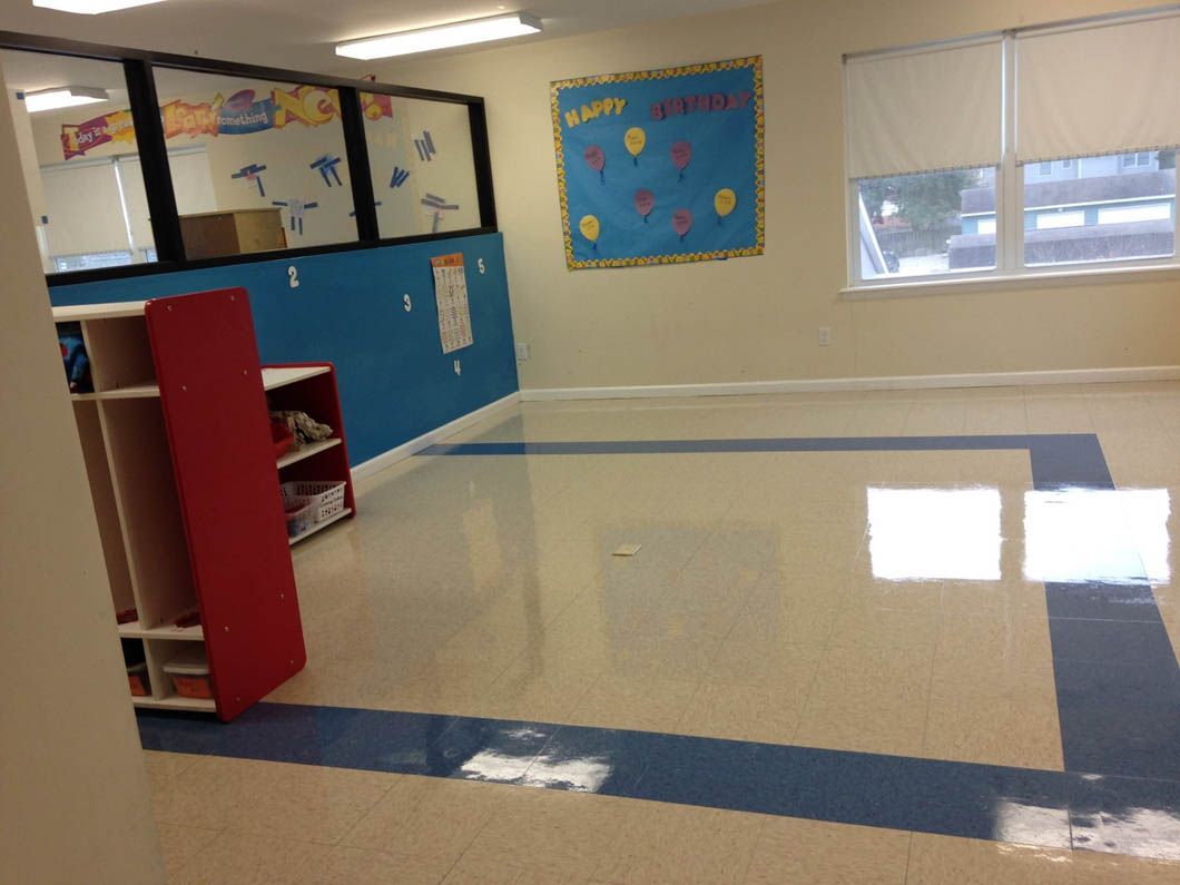 Empty classroom with blue and white floor, red cabinet, blue wall, and bulletin board.