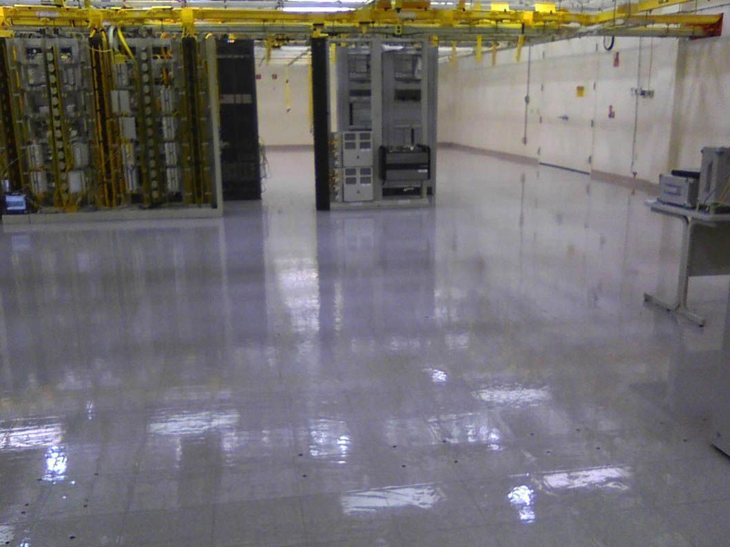 Data center interior with shiny, light-colored floor, server racks, and overhead cable management.