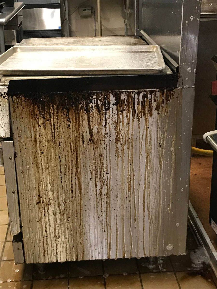 Stainless steel kitchen appliance covered in dark grease streaks.