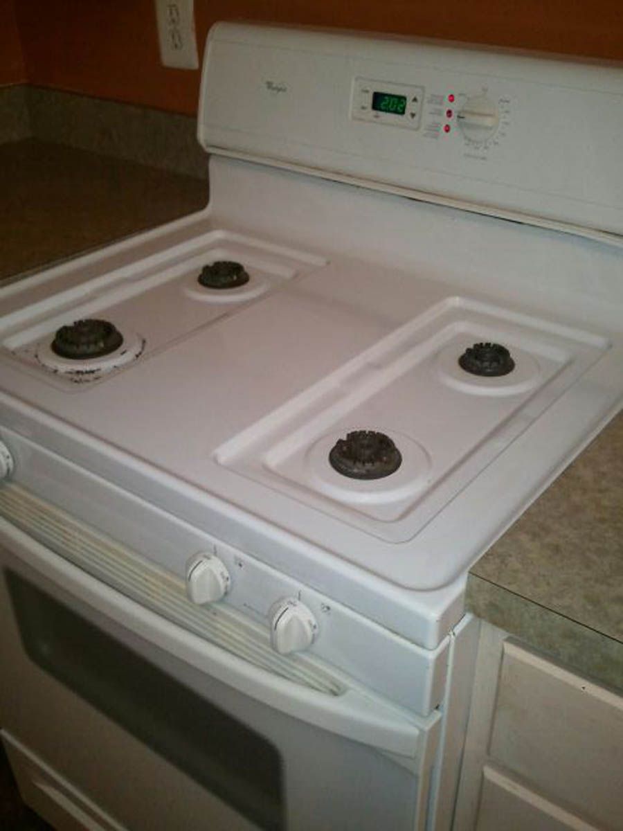 White gas stove with four burners, control knobs, and digital display.