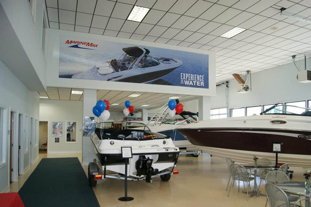 Boats displayed inside a showroom; a large banner advertises a boat, balloons are present.