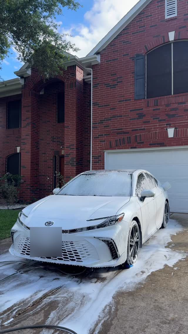 White Toyota Camry covered in foam in a driveway, Ongowash mobile detailing serving Bellaire, TX