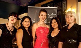 A woman in a red dress is standing next to three other women