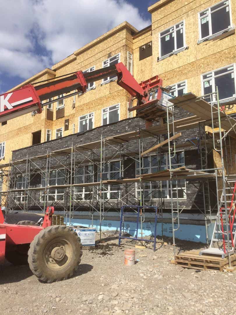 Construction site with scaffolding and a red lift beside a yellow building exterior