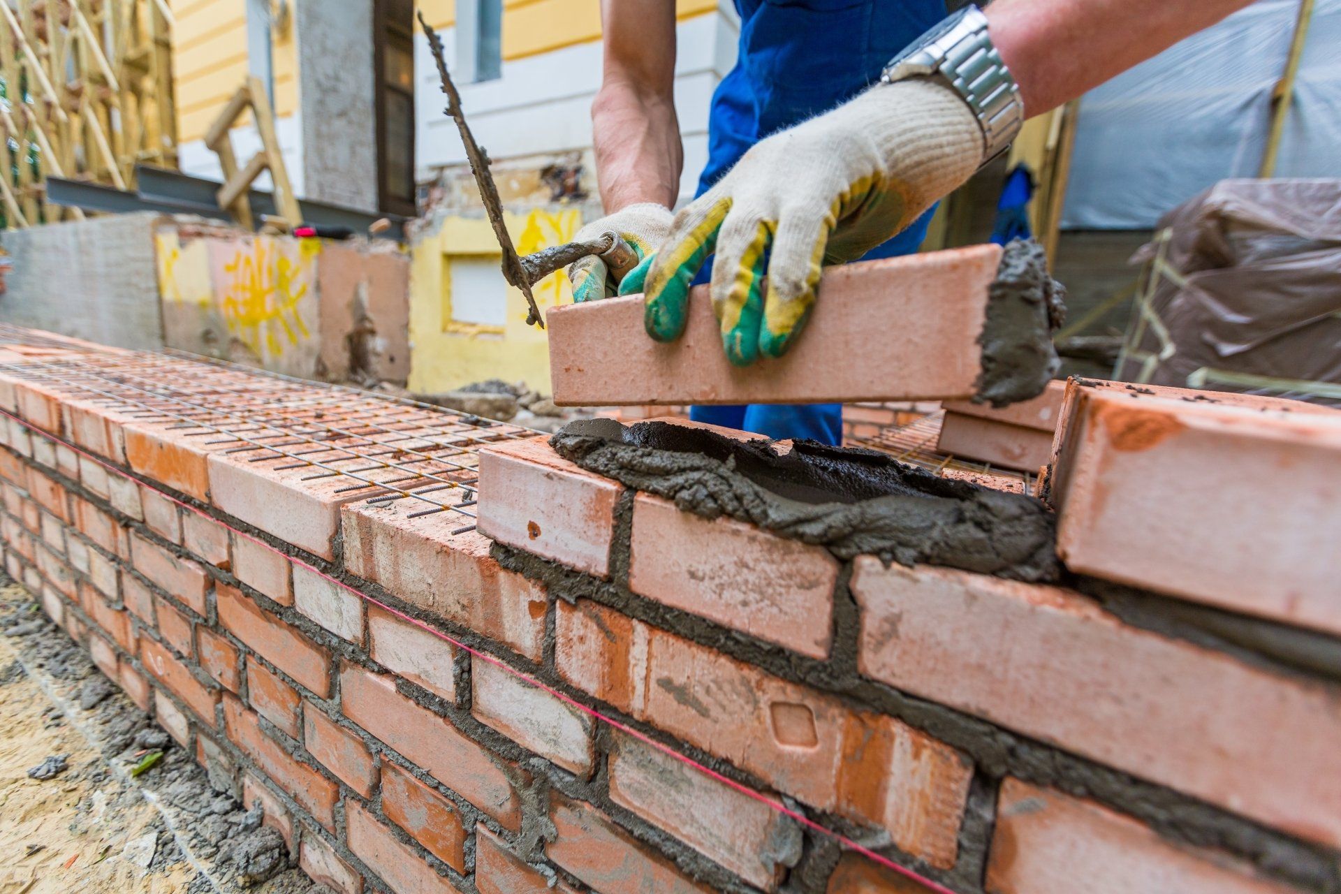 Bricklayer spreading mortar on a brick wall at a construction site
