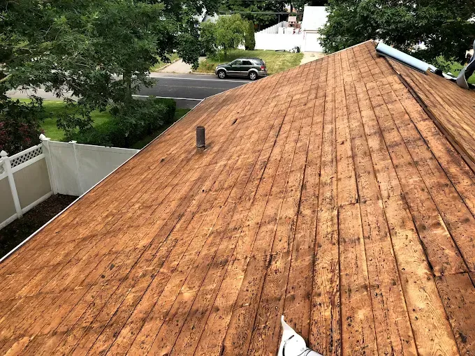 Orange shingle roof seen from above, with trees, a fence, and a parked car nearby.