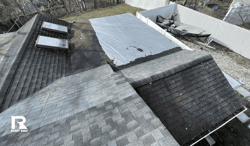 Aerial view of gray rooftop with skylights, vents, and sloped shingles in a residential area