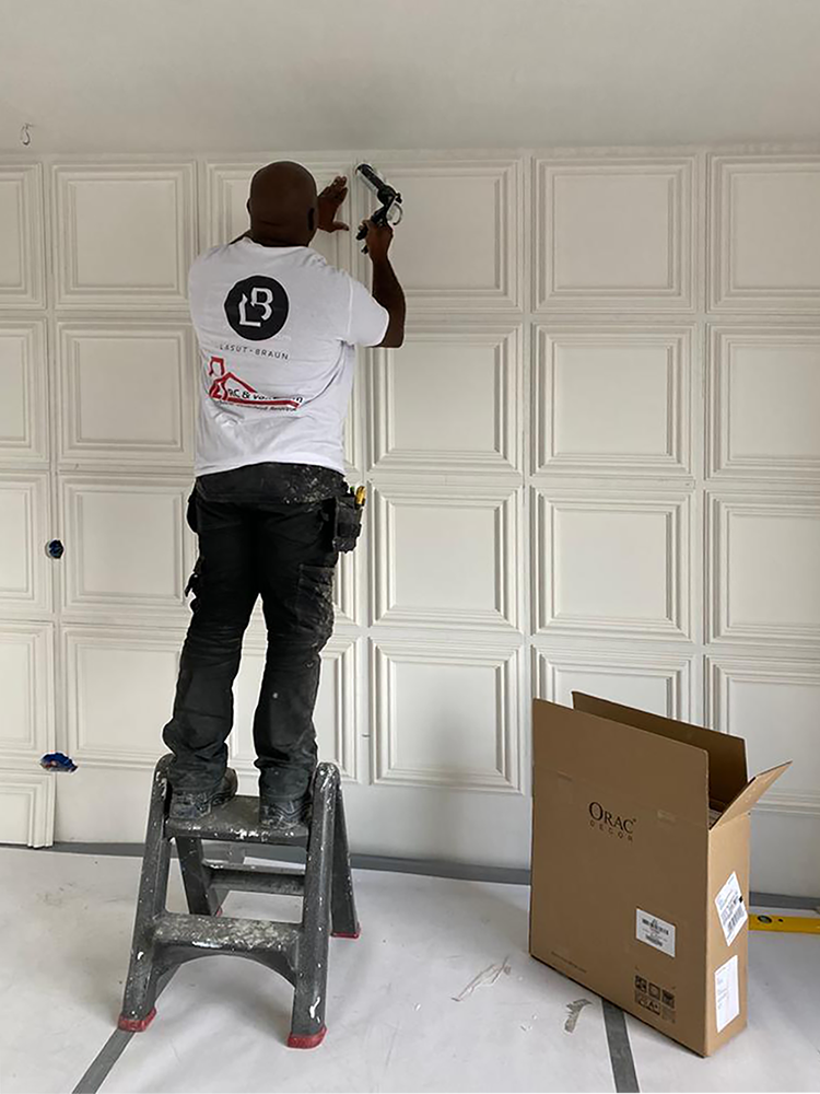 Een man staat op een ladder en werkt aan een muur.